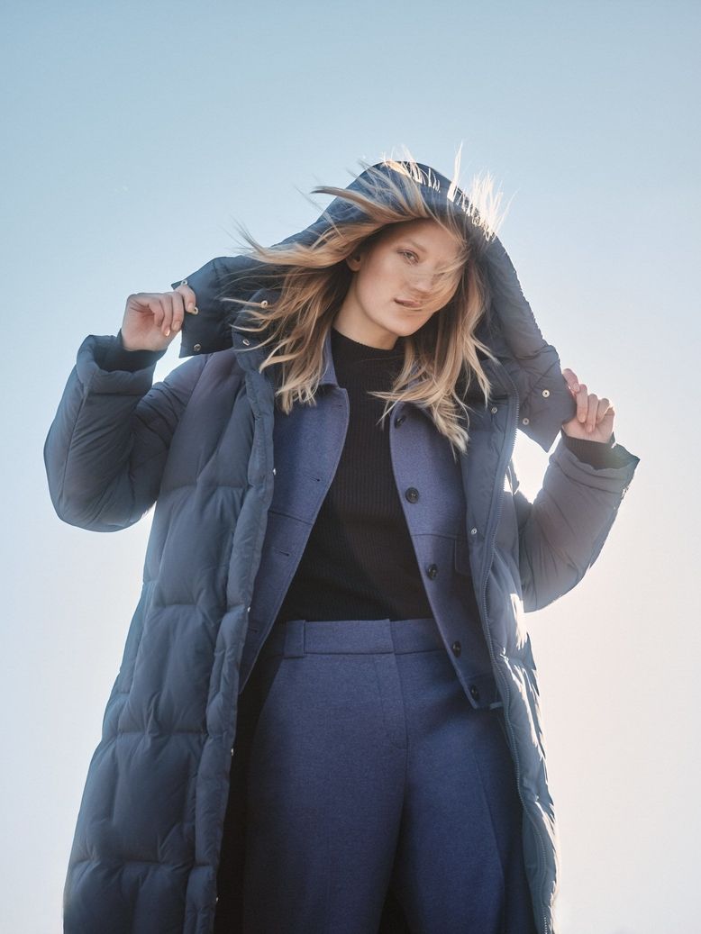 Model trägt ein blaues Outfit und einen blauen Mantel